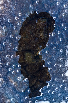 Drops of water collect under the thin ice